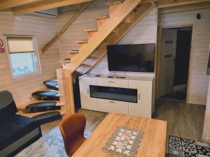 ein Wohnzimmer mit einem großen TV und einer Treppe in der Unterkunft Domki Przydwórz 