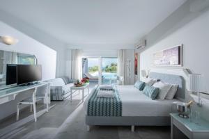 Rethymno Mare Royal & Water Park في سْكاليتا: غرفة معيشة بيضاء مع سرير ومكتب