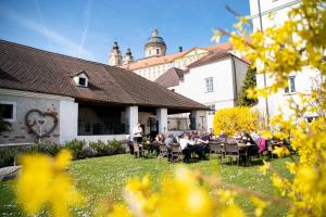 un grupo de personas sentadas en mesas frente a un edificio en Rathauskeller Melk, en Melk