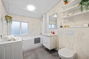 a white bathroom with a tub and a toilet and a sink at Venture Vacations - Best Possible Location-Laugavegur Luxury Loft in Reykjavík