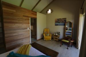 een slaapkamer met een houten muur en een gele stoel bij Gemstone Farm in Plettenbergbaai