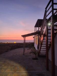 une maison avec un escalier à côté d'un coucher de soleil dans l'établissement Casa del Norte: Casa del Norte: Mediterranean Charm in Lobitos, Peru - Ideal Surf Haven for All Levels, à Lobitos
