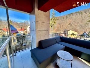 a blue couch on a balcony with a view at SINAI APH Apartments in Sinaia