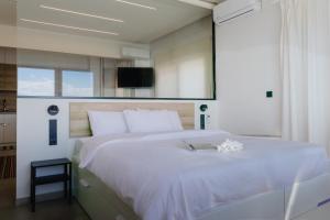 a bedroom with a white bed with a tv on the wall at Lighthouse apartments in Alexandroupoli