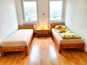 two beds in a small room with two windows at Private apartments with direct subway entrance in Fürth