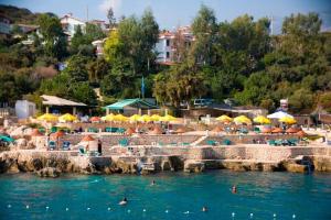 a beach with umbrellas and people in the water at Aquarius Hotel in Kaş