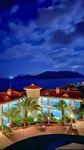 a large building with palm trees and the ocean at night at Aquarius Hotel in Kaş