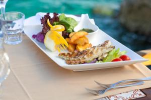 a plate of food with fish and vegetables on a table at Aquarius Hotel in Kaş