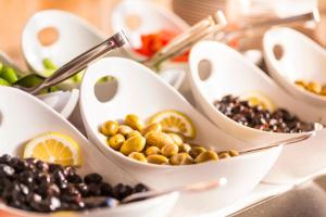 a buffet with white dishes filled with olives and fruit at Aquarius Hotel in Kaş