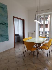 La Terrazza Apartment,a 50 mt dal mare في فاراتسي: غرفة طعام مع طاولة زجاجية وكراسي صفراء