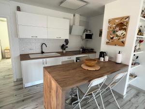 a kitchen with a wooden table and white cabinets at SUL MARE in Puerto de Santiago