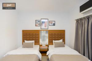 two beds in a room with white walls at Almanzel Sheikh Zayed in 6th Of October