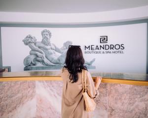 Meandros Boutique & Spa Hotel - Adults Only في كالاماكي: امرأة تبحث في عرض في متحف