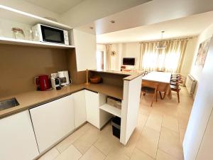 a kitchen with white cabinets and a dining room with a table at Charming apartment in La Fosca Beach in Palamós