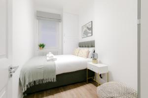 Luxury Apartments - Fitzrovia في لندن: غرفة نوم بيضاء بها سرير ونافذة