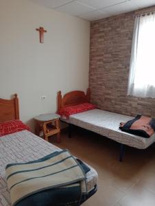 um quarto com duas camas e uma cruz na parede em Albergue Santa Ana em San Martín del Camino