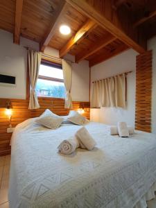 1 dormitorio con 1 cama blanca grande y 2 toallas en Cabañas del Arroyo en San Martín de los Andes
