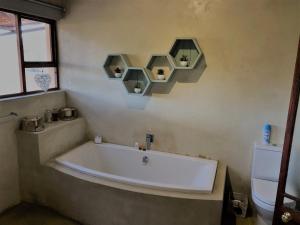 a bath tub in a bathroom with two shelves on the wall at Oaksrest Vineyards Guest Farm in Ladismith