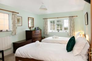 a bedroom with two beds and a dresser and two windows at Woodcutter's Cottage - Peaceful Country Retreat! 