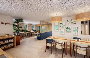un restaurant avec des tables et des chaises ainsi qu'une salle à manger dans l'établissement Résidence Prestige Odalys Le Riviera, à Hyères