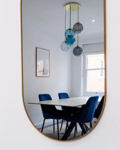Espejo comedor con mesa blanca y sillas azules en Prime Central London Residences, en Londres