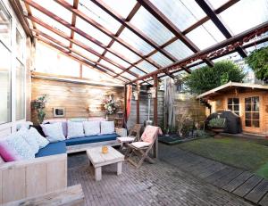 eine Terrasse mit einem blauen Sofa und einem Glasdach in der Unterkunft Hosted by Wendy with garden in Den Haag
