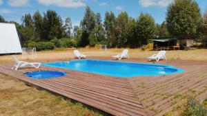 a swimming pool with chairs and a wooden deck at Travesía Rukamanque Lodge in Temuco