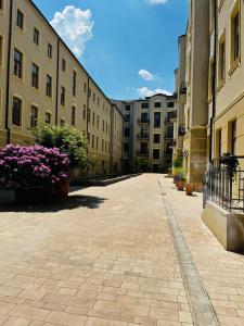 an empty courtyard of a building with pink flowers at Piotrkowska 37 - Romantyczna Przystań dla Dwojga in Łódź