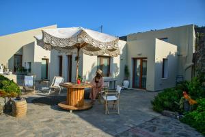 a woman standing under an umbrella on a patio at Villa Marenosta in Ermoupoli