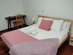 uma cama com almofadas brancas e cor-de-rosa e uma secretária. em El rincón de Leny em Cangas de Morrazo