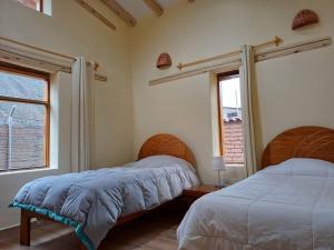 2 Betten in einem Schlafzimmer mit 2 Fenstern in der Unterkunft Cute House Surrounded by Nature in Yucay