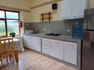 a kitchen with white cabinets and a table in it at Cute House Surrounded by Nature in Yucay