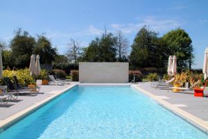 a swimming pool with chairs and umbrellas in a backyard at Hotel Château de la Barbinière in Saint-Laurent-sur-Sèvre