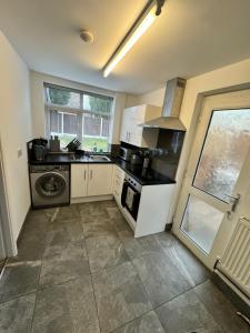 a kitchen with a stove and a washer and sink at West Midlands Contractors, Nurses and Families 