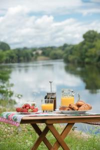 stolik piknikowy z jedzeniem i widokiem na rzekę w obiekcie Le Manoir de la Riviere w mieście Saint-Seurin-de-Prats