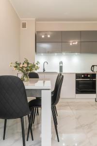 a kitchen with a table and black chairs at Flatbook Apartamenty - Jantar Bursztynowe Osiedle in Jantar