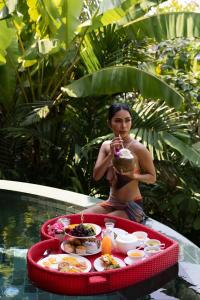 Three Monkeys Villas في شاطيء باتونغ: امرأة جالسة في حمام السباحة مع صينية من الطعام