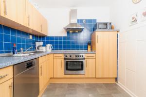 a kitchen with wooden cabinets and blue tiles at Admiralskoje direkt am Hafen in Flensburg