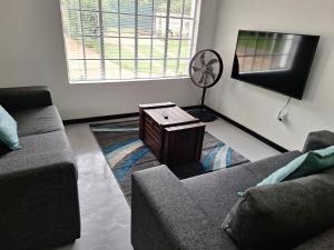 a living room with a couch and a fan at Siesta Cottage in Howick