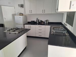 a kitchen with black counter tops and white cabinets at Siesta Cottage in Howick +20 photos