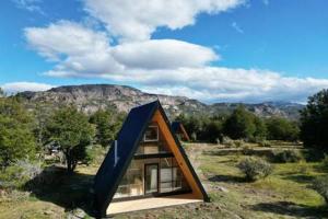 une petite maison avec un toit bleu dans un champ dans l'établissement OUTSCAPE l Cabaña Familiar en mejor sector de Cerro Castillo, à Villa Cerro Castillo