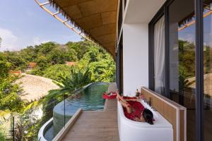 Three Monkeys Villas في شاطيء باتونغ: طفل في حوض استحمام في شرفة مع مسبح