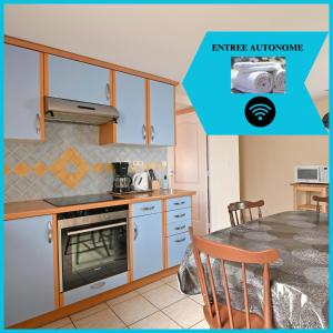 a kitchen with white cabinets and a table and a dining room at La Petite Maison Blanzy in Blanzy