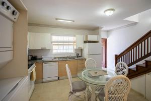 a kitchen with a glass table and chairs and a kitchen with a staircase at Whitesands G6 by Barbados Sothebys International Realty in Saint Peter