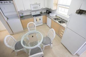 a kitchen with a table and chairs and a white refrigerator at Whitesands G6 by Barbados Sothebys International Realty in Saint Peter