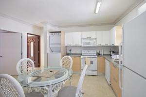 a kitchen with a glass table and white cabinets at Whitesands G6 by Barbados Sothebys International Realty in Saint Peter