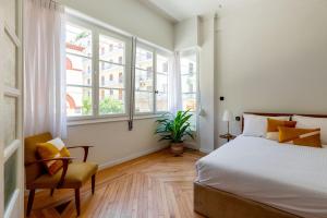 une chambre avec un lit, une chaise et des fenêtres dans l'établissement The Met by Zoia Living, à Athènes