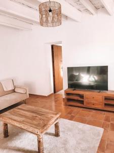 uma sala de estar com uma televisão grande e uma mesa de centro em Casa Om em Dosríus