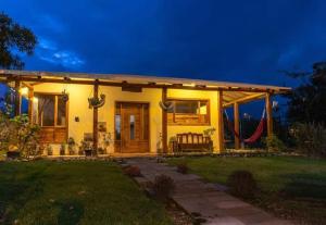 una pequeña casa amarilla con porche por la noche en La casa del colobri, en Cotacachi