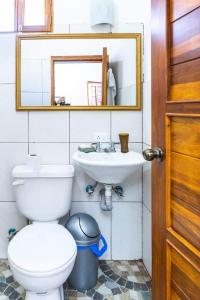 ein Badezimmer mit einem WC, einem Waschbecken und einem Spiegel in der Unterkunft La casa del colobri in Cotacachi